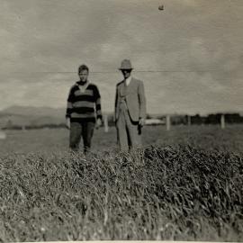 Farmer and son standing in a field - 1 of 2